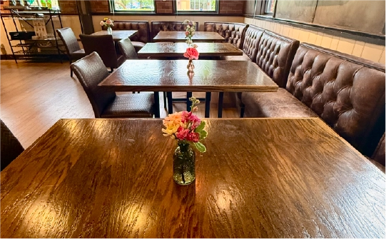 Tufted leather booth seating and wood dining tables with fresh flower vases set up for a private event at the Fortin Ironworks Event Lounge in Columbus Ohio
