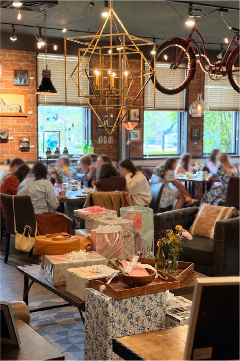 Guests gathered for a private bridal shower at the Fortin Ironworks Event Lounge in Columbus Ohio, with gift tables in the foreground and a geometric gold chandelier overhead