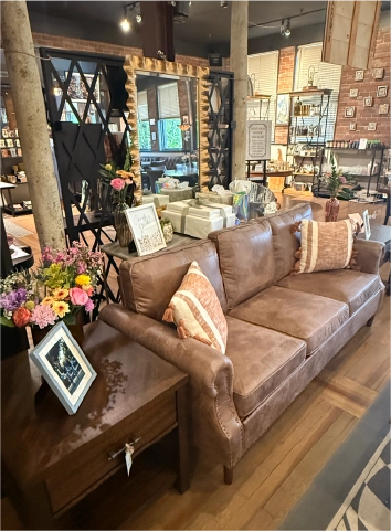 Leather sofa with decorative pillows and fresh flowers inside the Fortin Ironworks Event Lounge, where guests can browse The Market's rotating inventory during events